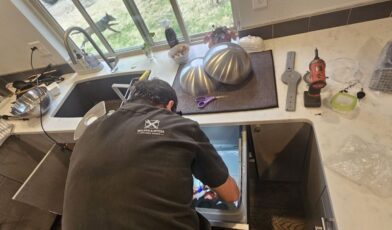 Wilson and Myers technician inspecting a dishwasher that is not drying dishes properly in a Denver Metro home