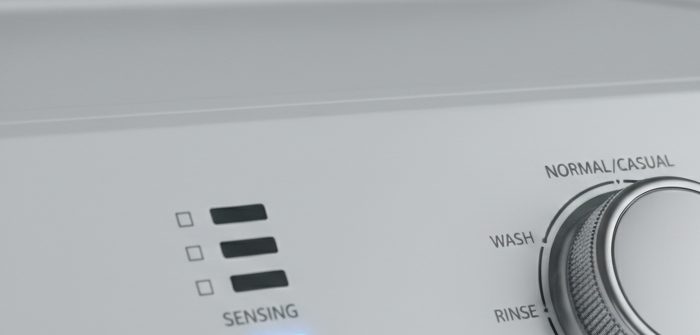 Maytag top-load washer control panel with SENSING indicator label visible above blue LED; washer stuck on sensing cycle