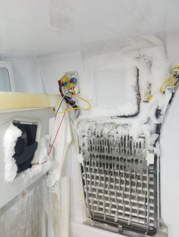 Samsung refrigerator evaporator coil with heavy ice buildup blocking airflow, causing the fridge to stop cooling