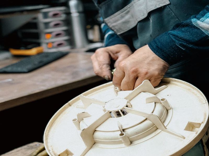 Appliance technician examining evaporator fan motor component on workbench; Sub-Zero freezer repair requires certified professional