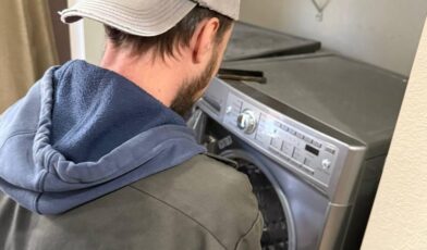Wilson & Myers technician inspecting a front-load washer door during a washer leaking from bottom repair call in the Denver Metro Area