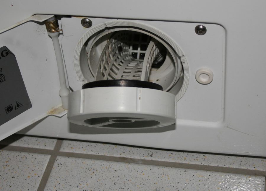 AEG front-load washer lower access panel open, showing round drain pump filter housing; how to locate the filter