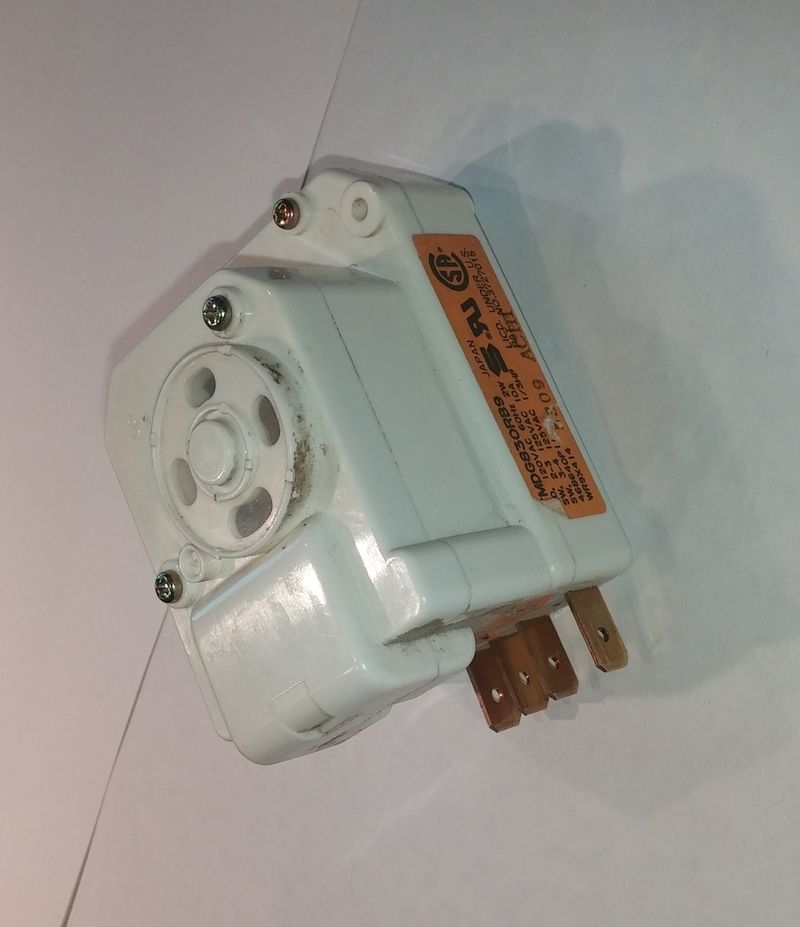 Defrost timer from a household refrigerator showing electrical connectors and mechanical timer mechanism