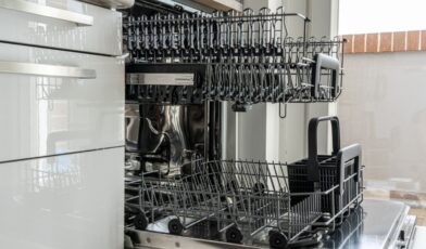 Open dishwasher interior in a residential kitchen with the bottom rack and filter area visible