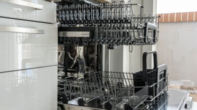 Open dishwasher interior in a residential kitchen with the bottom rack and filter area visible