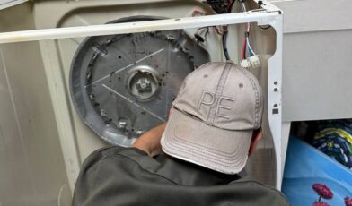 Wilson and Myers technician inspecting the interior of an open dryer cabinet during a dryer not spinning repair in Denver