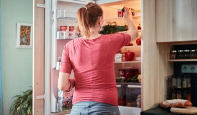 Homeowner reaching into an open refrigerator in a bright residential kitchen
