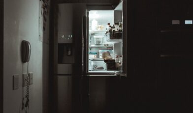Open refrigerator interior in a residential kitchen with empty compartments and natural light