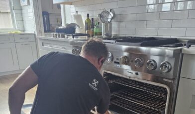 Wilson and Myers technician servicing an electric range oven in a Denver kitchen