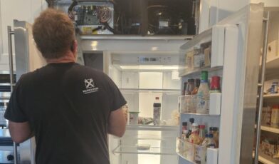 Wilson and Myers technician inspecting the fresh food compartment of an open refrigerator in a Denver Metro kitchen