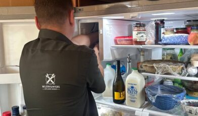 Wilson and Myers technician checking the freezer compartment of a home refrigerator on a Denver service call