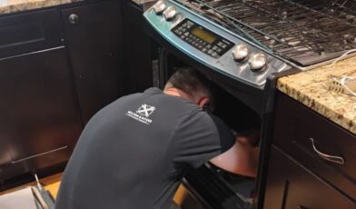 Wilson and Myers technician diagnosing a gas oven interior on a service call in Denver Metro