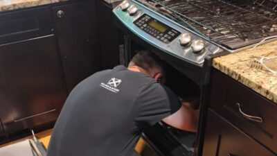 Wilson and Myers technician diagnosing a gas oven interior on a service call in Denver Metro