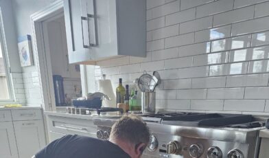 Wilson and Myers technician inspecting a gas range surface burner cooktop during a Denver appliance repair service call