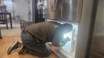 Wilson and Myers technician inspecting a French door refrigerator that stopped cooling in a Denver Metro home