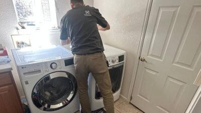 Wilson and Myers technician servicing a front load dryer in a Denver Metro laundry room