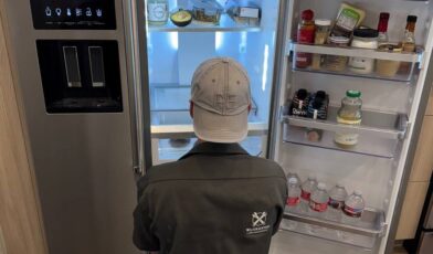 Wilson and Myers technician inspecting a side-by-side refrigerator water and ice dispenser during a Denver appliance repair call