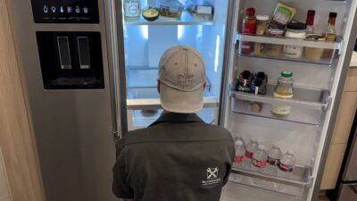 Wilson and Myers technician inspecting a side-by-side refrigerator water and ice dispenser during a Denver appliance repair call