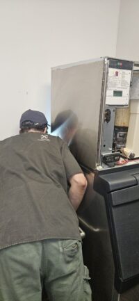 Technician servicing a commercial ice machine in a Denver Metro kitchen