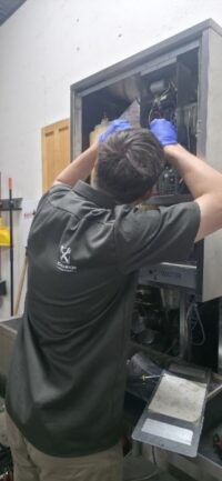 Technician inspecting an ice machine in a commercial kitchen