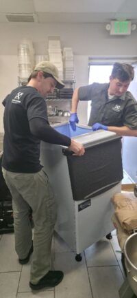 Technicians moving a commercial ice machine for service