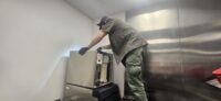Technician working on an ice machine in a stainless kitchen