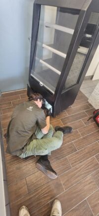Technician servicing a commercial glass door refrigerator in Denver Metro