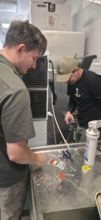 Technicians working on a commercial prep table refrigeration unit