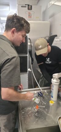 Two technicians servicing commercial kitchen refrigeration in Denver Metro