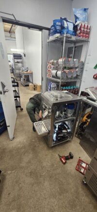 Technician servicing shelving refrigeration in a commercial space