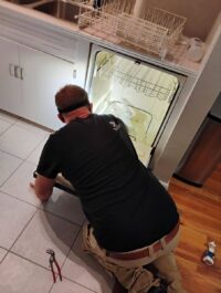 Technician checking the bottom rack and spray arm of a dishwasher