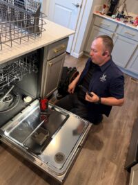 Technician checking wash results in an open dishwasher