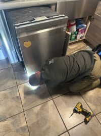 Technician removing a dishwasher panel to reach the controls