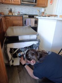 Technician working under a dishwasher on the wiring