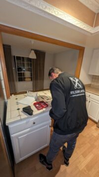 Technician diagnosing a dishwasher in a Denver Metro kitchen