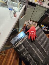 Technician handling a dishwasher door panel during a seal repair