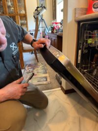 Technician reaching inside a dishwasher door assembly