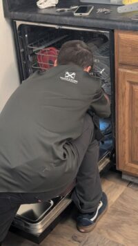 Technician inspecting the door area of a dishwasher