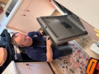 Technician checking the lower door seal of a dishwasher