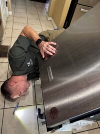 Technician working on a dishwasher door panel in a Denver kitchen
