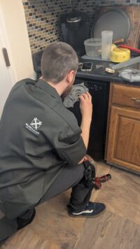 Technician inspecting a dishwasher interior for residue