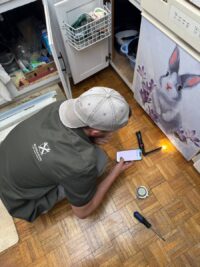 Technician servicing a dishwasher under the counter