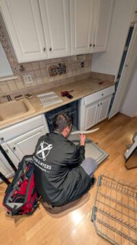 Technician working on a dishwasher in a Denver Metro kitchen