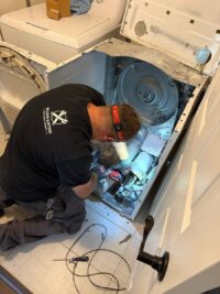 Technician tracing dryer heating circuit wiring with the front panel off