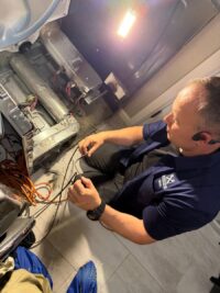 Technician testing dryer electrical connections during a no heat repair