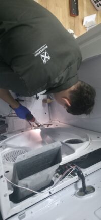 Technician checking dryer components with a work light