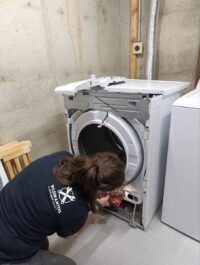 Technician working on a dryer with the front panel removed
