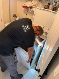 Technician removing a dryer panel to reach the start switch