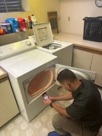 Technician reaching into the top of a dryer cabinet