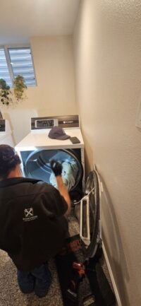 Technician servicing a dryer in a Denver Metro laundry closet